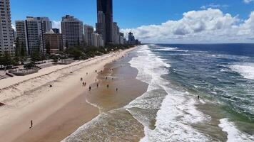 Aerial footage of Gold Coast beach with people walking, skyscrapers, and ocean waves under bright sunlight video