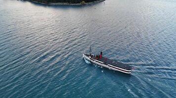 A steamship glides across Lake Wakatipu, surrounded by serene waters and distant mountains, captured in soft evening light video