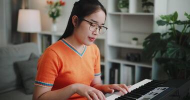 Beautiful woman playing the keyboard with happy smile in cozy living room. Enjoy a relaxing weekend activity video