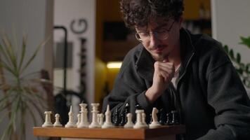 Contemplative Caucasian guy player grandmaster playing chess board game at home pensive smart male moving pawn piece chessboard thinking man pondering strategy gaming tactics preparing for tournament video