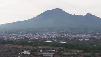 Aerial view of Pompeii's ancient ruins and modern cityscape, with Mount Vesuvius in the background. The pans slowly across the lush landscape. video