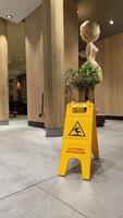 25.03.2025 Germany. Caution Wet Floor Sign in Modern Wooden Interior with Decor in McDonalds. Bright yellow caution wet floor sign displayed on tiled floor in a cozy wooden interior with decor. photo