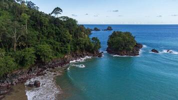 Scenic coastal view with turquoise waters, lush greenery and small islands at Lenggoksono Beach photo