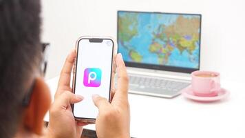 Yogyakarta, Indonesia, 2025 - Man holding smartphone with Picsart, creative editing platform application is loaded on the screen isolated on white background photo