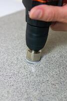 rotating diamond core drill bit starts drilling into a stone slab photo