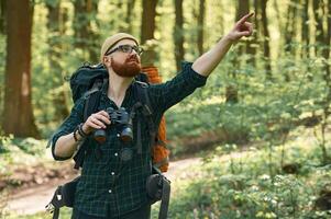 Discovering new place with binoculars... Bearded man is in the forest at daytime photo