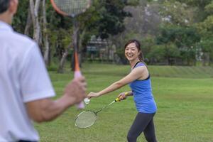 young attractive asian woman enjoy holiday time playing badminton with senior father outdoors in the park,family lifestyle sport recreation concept photo
