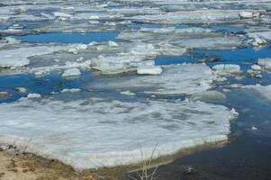 Massive ice floes slowly move along the Bakhthiyar River as the ice breaks up during the spring thaw in a quiet, remote region. photo
