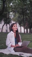 A successful business woman rehearses her speech before speaking to a large audience. The girl is sitting at the computer on the grass in the park. Vertical format for the phone. video