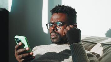 Man looks at phone puts on earphone. video