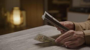 Hands counting stack of US dollar bills on table video