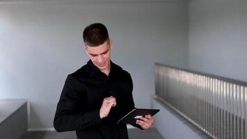 tablet man guy looking at his fingers after boxing holding a tablet in a black shirt standing in the hall video
