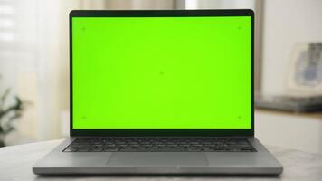 Laptop with green screen on table in modern indoor setting video
