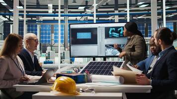 Shareholders discussing future investment opportunities in sustainable energy manufacturing. Management executives and investors in solar panels plant reviewing solar technology reports, camera A video