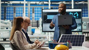 Teamworking factory colleagues researching new photovoltaics materials. Team of solar panel manufacturing plant researchers developing new solar energy systems prototypes, camera B video