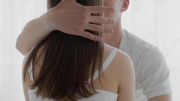A young couple enjoys an intimate moment in their bedroom, surrounded by soft morning light. They express love and affection while sitting closely together, emphasizing their connection. video
