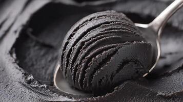 Black ice cream scoop resting on a silver spoon atop a creamy base in a dessert preparation setting photo
