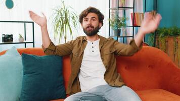 Arabian man smiling friendly at camera, waving hands gesturing hello, hi, greeting at home on sofa video