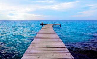 A wooden pier that stretches out to the sea with blue sky for travel and vacation photo