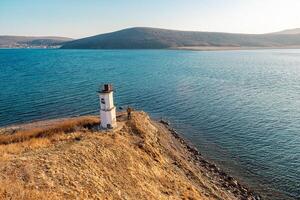 View of the lighthouse on the shore of the Sea of Japan and the island on the horizon photo