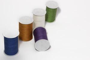 Spool of sewing thread, isolated on white background. Colored yarns used by factories in the clothing industry. Threads wound on the spool. Colored reels photo