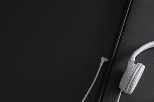 Horizontal banner with place for text - White headphones and part of notebook on a black background. photo