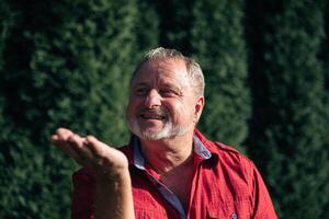 oyful Senior Man in Red Shirt Enjoying a Sunny Day in the Garden photo