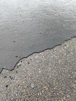 Access road with deteriorating asphalt, gravel, and rainwater accumulation in Wales. photo