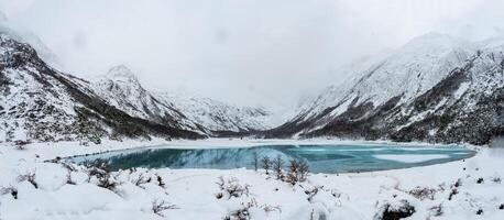 Aerial view of glacier water Emerald Lake in the mountain summit. Turquoise color water lake surrounded by forest and rocky mountain peaks. photo