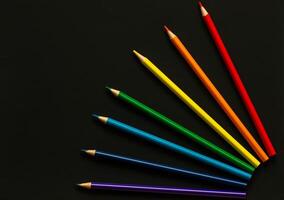Bright school supplies on plain background. Assortment of colorful stationery, pencil, set of colored pencils, rainbow color order on dark background photo