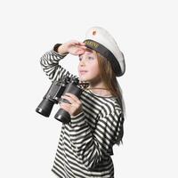 Portrait of a sailor girl on a white background teenage girl in a sailor suit with a binocular looking into the distance. photo