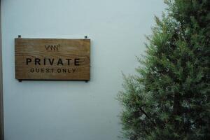 The empty wooden plate for putting some word hanging on the white wall with the tree aside photo