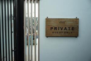 The wooden signboard with the words Private Guest Only hanging on the white wall photo