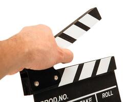 black movie clapper with white inscriptions in the hand on a white table photo