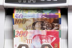 Israeli new shekel in the counting machine photo