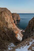 Mystical high cliffs rise above the sea. Harsh winter seascape. Place of power, calm of the elements. photo