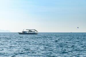 Landscape of a Boat floating in the blue sea with beautiful waves in the evening on the background of clear sky and island. at Koh Larn island. Panorama ocean. Pattaya, Thailand, ship, Vacation. photo