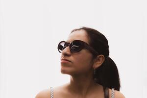 Woman with glasses and in front of a white background looks up in profile. photo