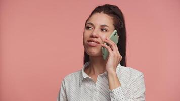 Smiling woman talking on phone against pink background video