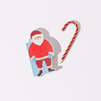 Christmas scene made with candy cane pencil and Santa Claus notebook on white background. Minimal Christmas and New Year concept. Writing letters to Santa idea. Xmas aesthetic. Flat lay. photo