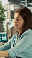Vertical Stressed worker in office sighs, burdened by too many documents to review. Tired employee at work feeling overworked while analyzing business performance metrics, camera B video