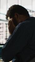 Vertical Worker feeling painful headache while working, suffering burnout while rushing to finish tasks before deadline. African american man in office having migraine after working overtime, camera A video