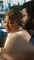 Vertical Supervisor in office discussing with employee about key performance indicators for revenue, profitability and operational efficiency. African american manager supervising employee at work, camera A video