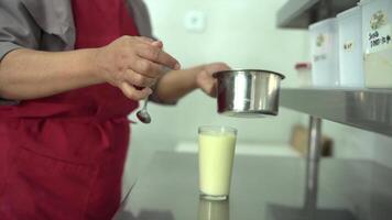 A man in an apron pouring milk into a glass video