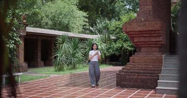 Solo Asian tourist enjoy takes photos with mobile phone while strolling around, admiring the peaceful atmosphere and cultural beauty of the place. video