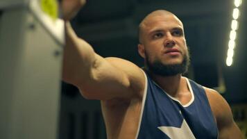 bald athletic man beard is engaged in leg exercises gym. He concentrates on his form while performing leg routines in well equipped fitness environment and says video