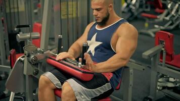 muscular bald man beard is actively engaged in leg exercises gym. Hi does leg extensions video