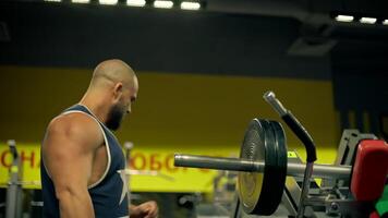 Bald athletic man beard works diligently on leg exercises using gym equipment. intense workout takes place in indoor gym setting focused on building strength and muscle video