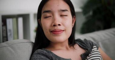 Handheld selective focus shot, Young woman relaxes on a comfortable sofa, enjoy wellbeing breathing fresh air in living room at home. video