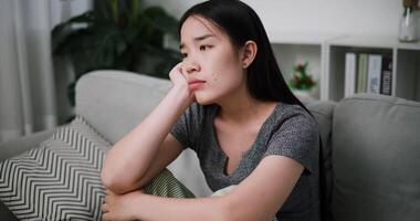Stressed woman sits alone on a sofa, thinking aimlessly, feeling worried about something. Life problems video